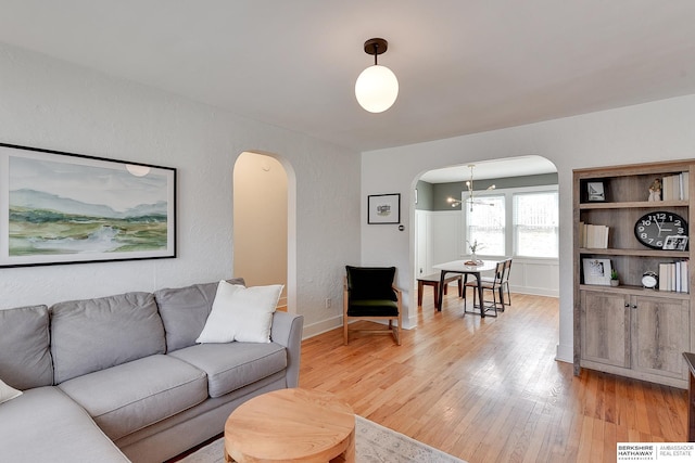 living area with visible vents, arched walkways, and light wood-style floors