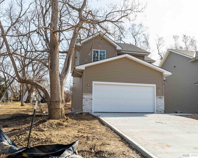 traditional-style home featuring stone siding, driveway, and an attached garage