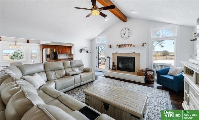 living area with a wealth of natural light, beamed ceiling, a high end fireplace, and ceiling fan with notable chandelier