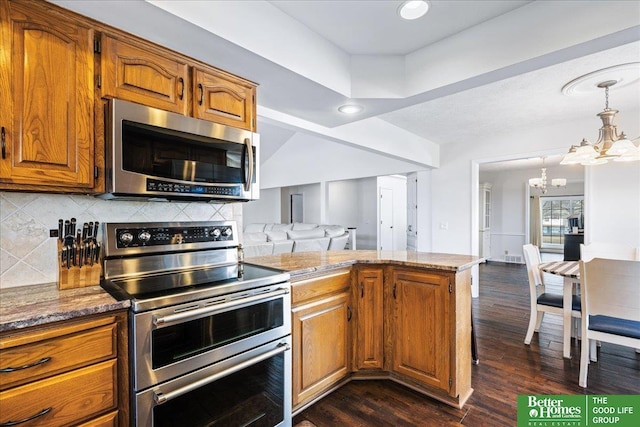 kitchen with backsplash, dark wood-type flooring, a chandelier, brown cabinets, and appliances with stainless steel finishes