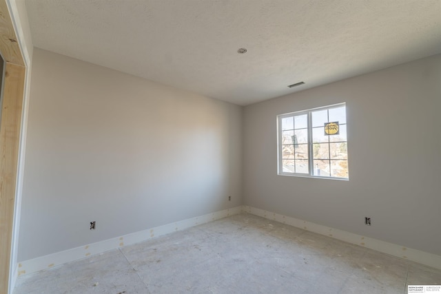 empty room featuring baseboards, visible vents, and a textured ceiling