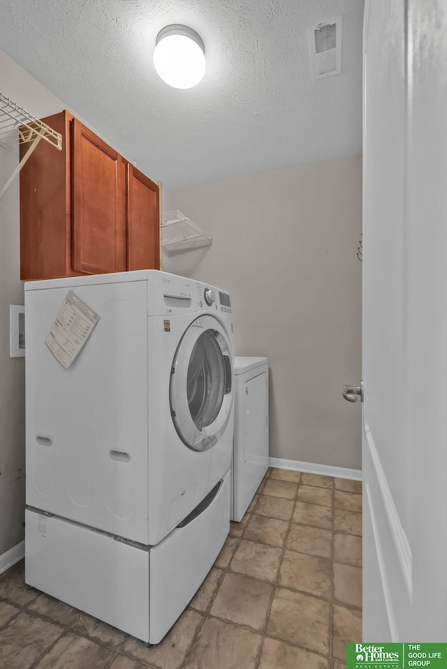 laundry area with a textured ceiling, cabinet space, visible vents, and washing machine and clothes dryer