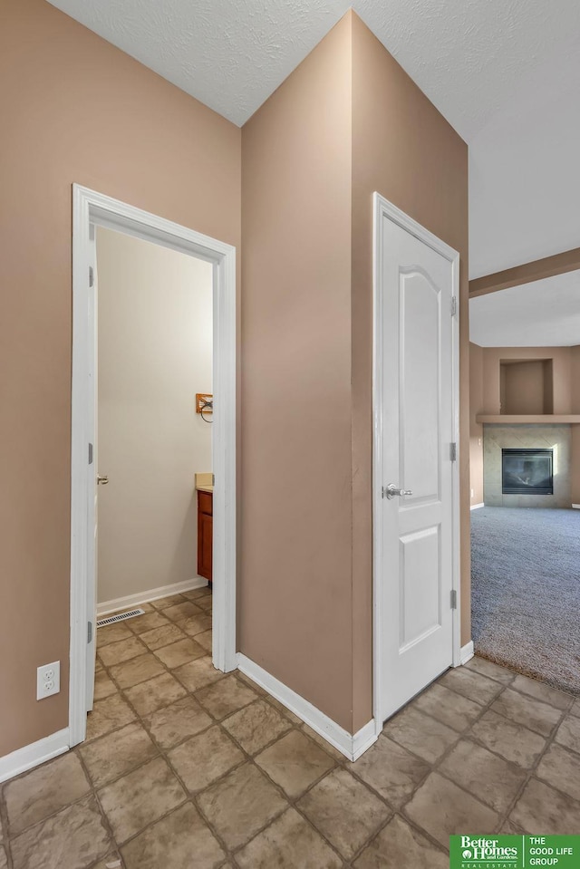 corridor featuring a textured ceiling and baseboards