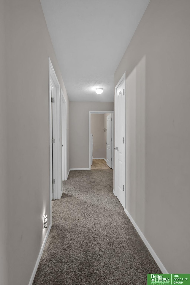 corridor featuring baseboards and carpet floors