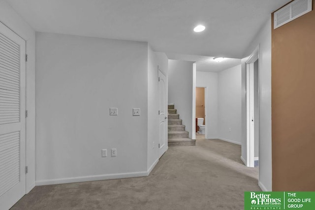 hallway with visible vents, carpet flooring, stairs, and baseboards