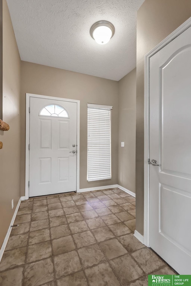 entryway with baseboards and a textured ceiling