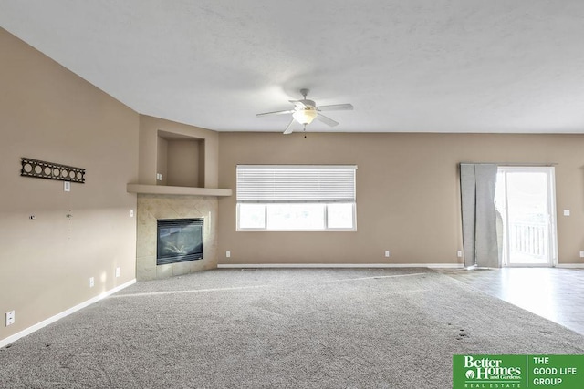 unfurnished living room with a tile fireplace, baseboards, carpet, and ceiling fan