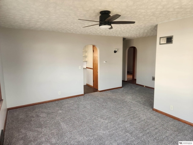 spare room with visible vents, a ceiling fan, arched walkways, carpet, and baseboards