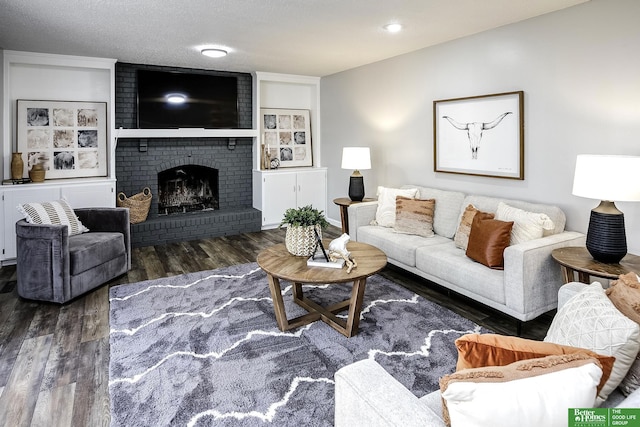 living room with a fireplace, a textured ceiling, and wood finished floors