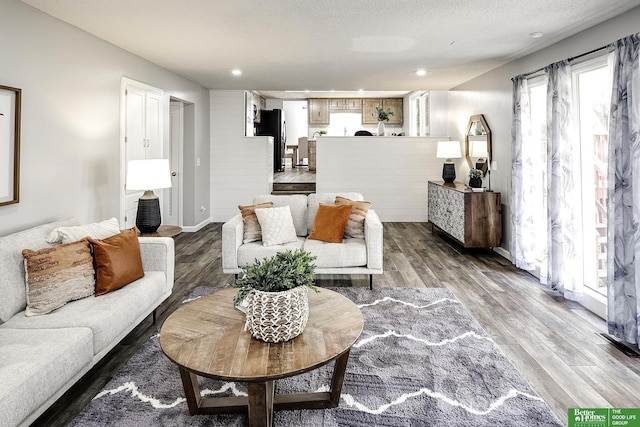 living room with recessed lighting, a textured ceiling, light wood-type flooring, and baseboards