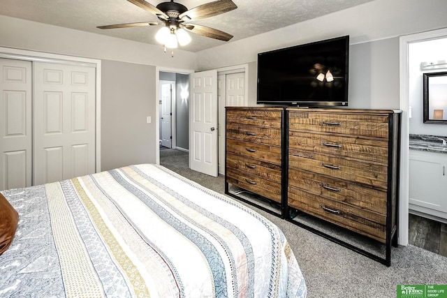 bedroom with ceiling fan, carpet, two closets, and a textured ceiling