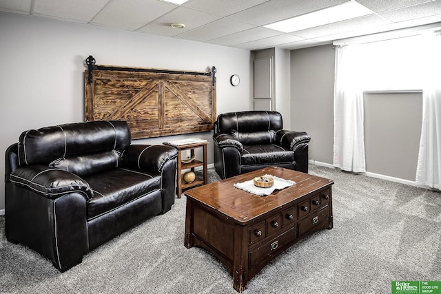 living area with a drop ceiling, baseboards, and carpet