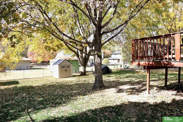 view of yard featuring a fenced backyard, a wooden deck, an outdoor structure, and a shed