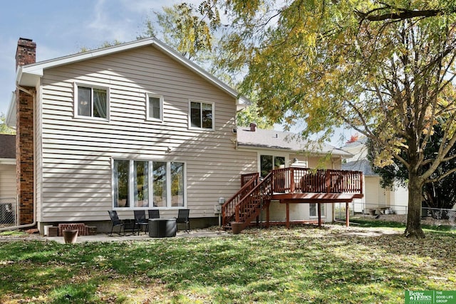 rear view of house with a lawn, fence, stairway, a wooden deck, and a chimney