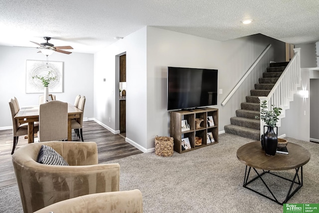 living area with baseboards, stairway, a textured ceiling, and ceiling fan