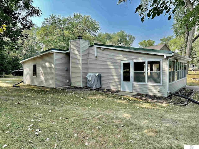 back of house with a lawn and a sunroom