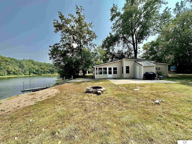 exterior space featuring a patio, a water view, a sunroom, and an outdoor fire pit