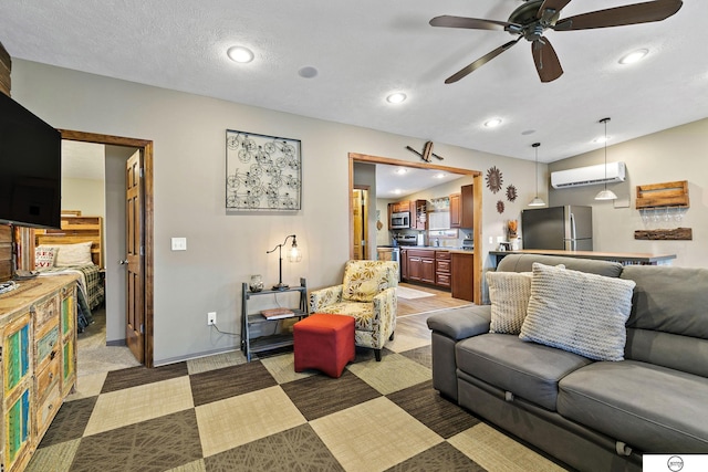 living area with baseboards, a wall unit AC, recessed lighting, a textured ceiling, and a ceiling fan