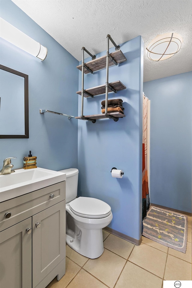 bathroom featuring tile patterned flooring, a textured ceiling, toilet, and vanity