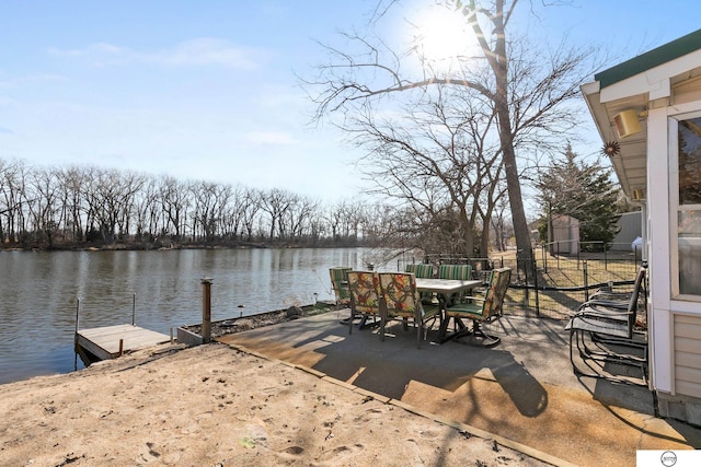 exterior space with outdoor dining area, a water view, and a boat dock