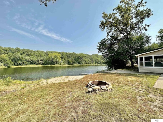 view of yard with a water view, a fire pit, and a wooded view