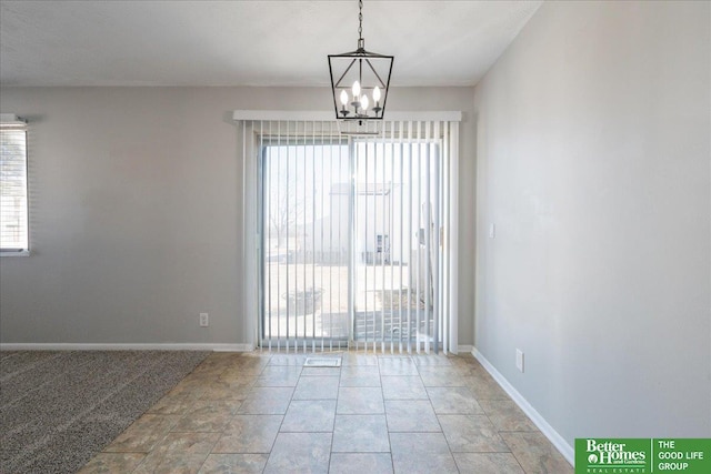 unfurnished room featuring baseboards, a healthy amount of sunlight, and a chandelier