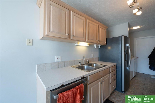 kitchen featuring a sink, light countertops, appliances with stainless steel finishes, a textured ceiling, and washer and clothes dryer