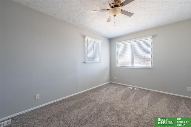 carpeted spare room featuring visible vents, baseboards, a textured ceiling, and ceiling fan