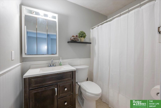 bathroom with vanity, toilet, and wainscoting