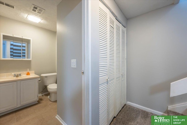 bathroom with vanity, toilet, visible vents, and a textured ceiling