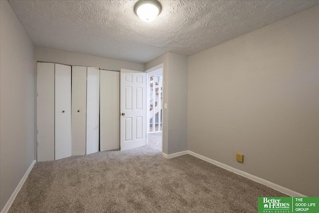 unfurnished bedroom with carpet flooring, baseboards, a closet, and a textured ceiling