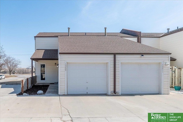 view of property with driveway, a garage, and roof with shingles