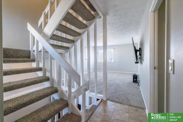 stairway featuring carpet flooring, baseboards, and a textured ceiling