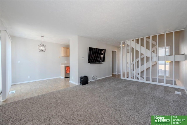 unfurnished living room featuring baseboards, stairs, a textured ceiling, light colored carpet, and a chandelier