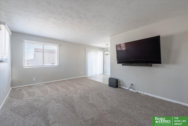 unfurnished living room featuring baseboards, a textured ceiling, and carpet flooring