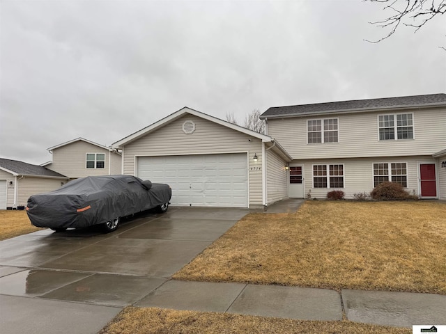 colonial home featuring an attached garage, concrete driveway, and a front lawn