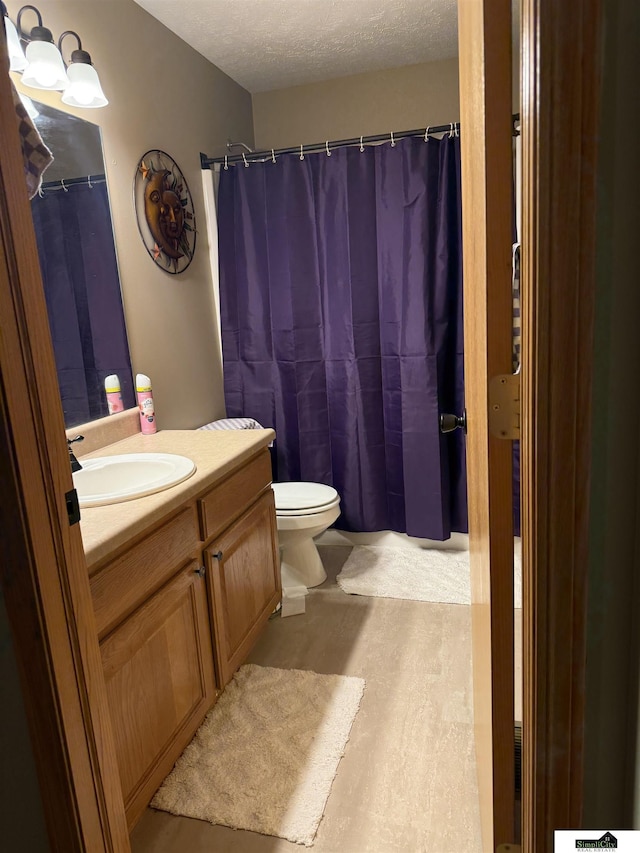 bathroom with vanity, toilet, and a textured ceiling