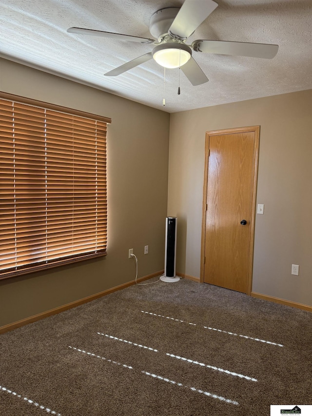 carpeted spare room with baseboards, a textured ceiling, and ceiling fan