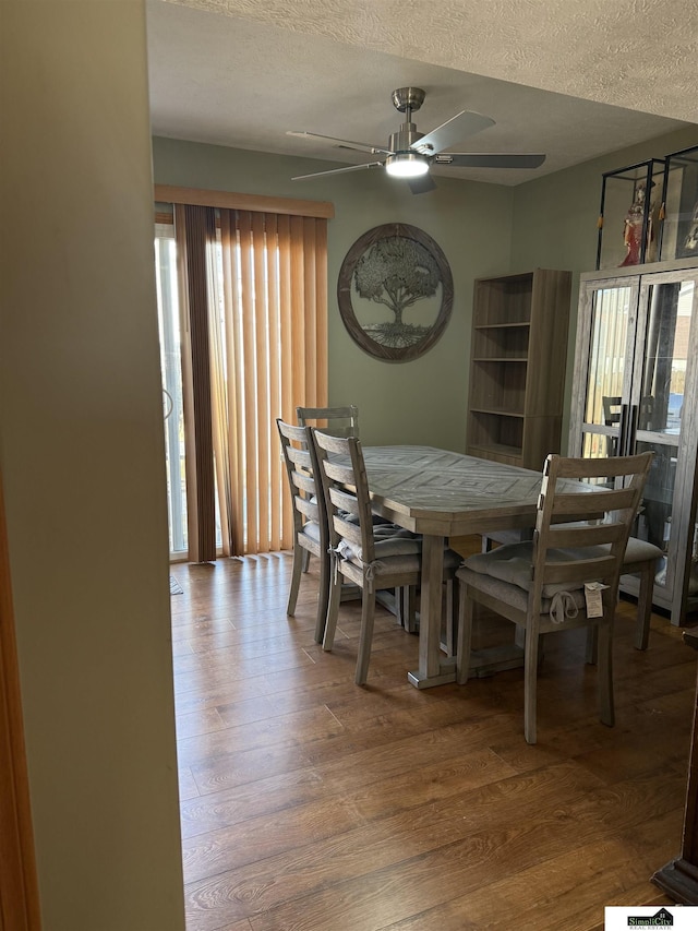 dining area with a textured ceiling, wood finished floors, and ceiling fan