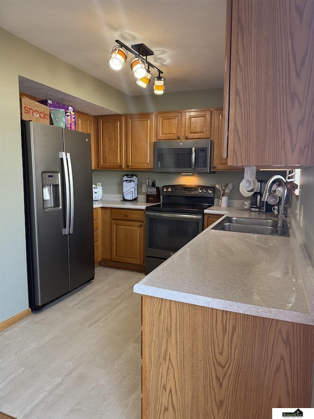 kitchen with brown cabinets, appliances with stainless steel finishes, light countertops, and a sink