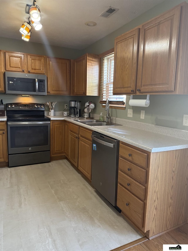 kitchen featuring visible vents, brown cabinets, a sink, appliances with stainless steel finishes, and light countertops