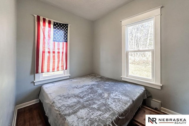 bedroom with wood finished floors, visible vents, and baseboards