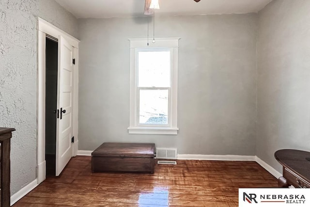 living area featuring plenty of natural light, baseboards, ceiling fan, and hardwood / wood-style floors