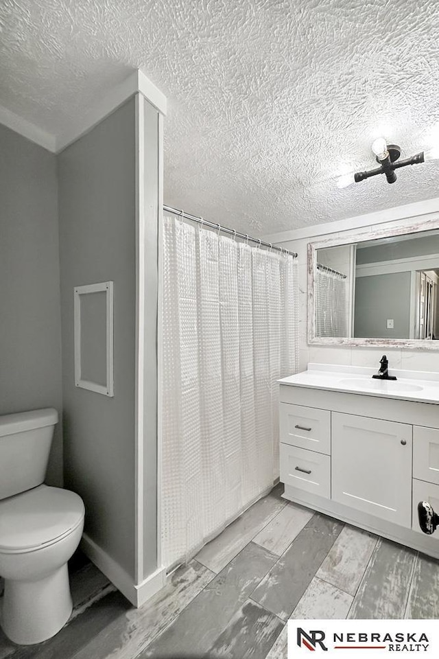 bathroom with a shower with shower curtain, toilet, vanity, and a textured ceiling