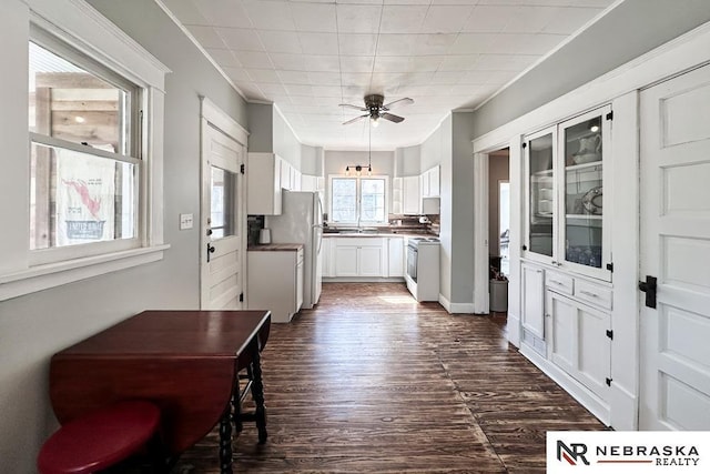 kitchen featuring dark wood finished floors, crown molding, white cabinets, and range