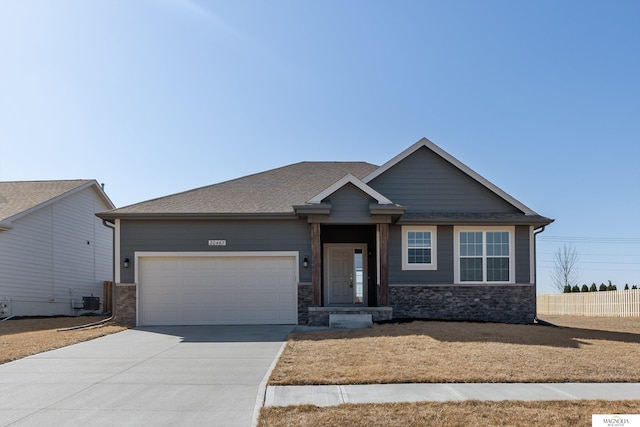 view of front facade featuring stone siding, an attached garage, concrete driveway, and roof with shingles