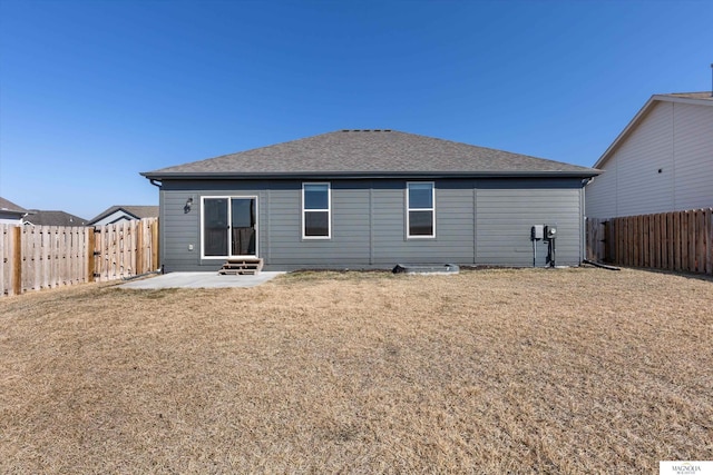 back of house with a patio area, a lawn, a fenced backyard, and roof with shingles