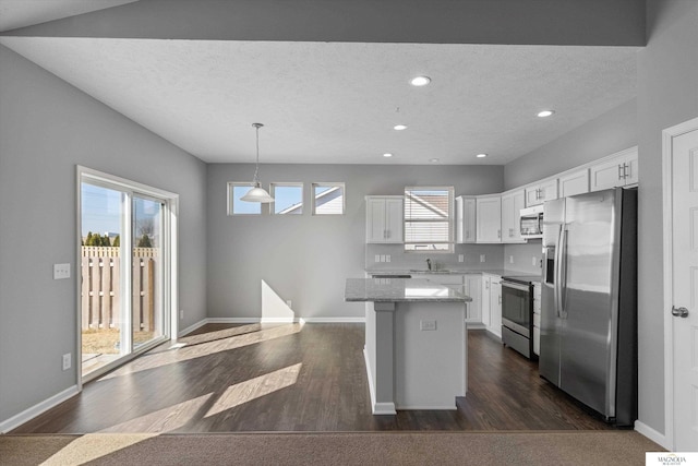 kitchen featuring dark wood finished floors, a center island, appliances with stainless steel finishes, and a sink