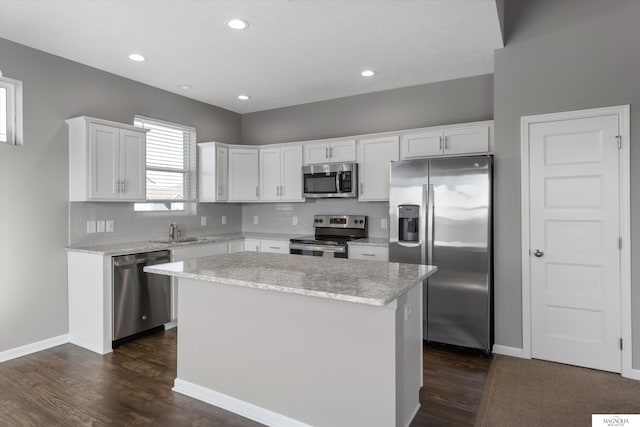 kitchen with white cabinets, tasteful backsplash, appliances with stainless steel finishes, and a center island