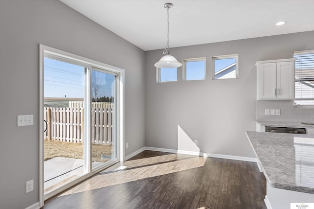 unfurnished dining area featuring recessed lighting, baseboards, and dark wood-style floors